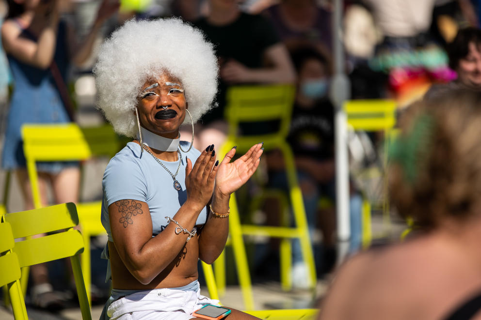 A person with a white afro applauds