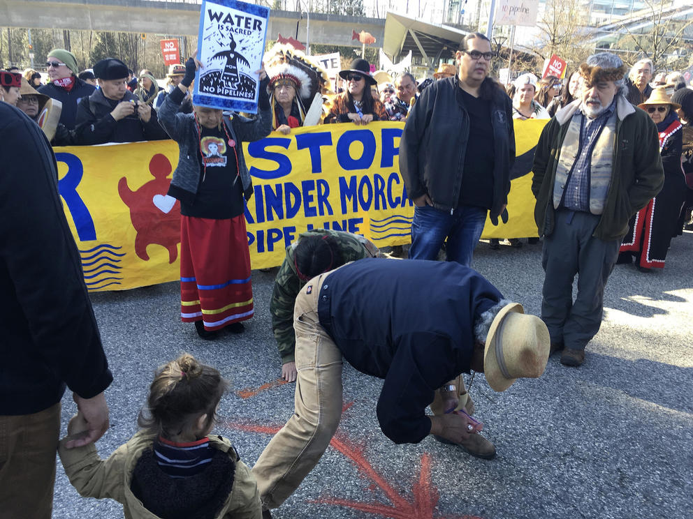 People gather in front of a yellow sign