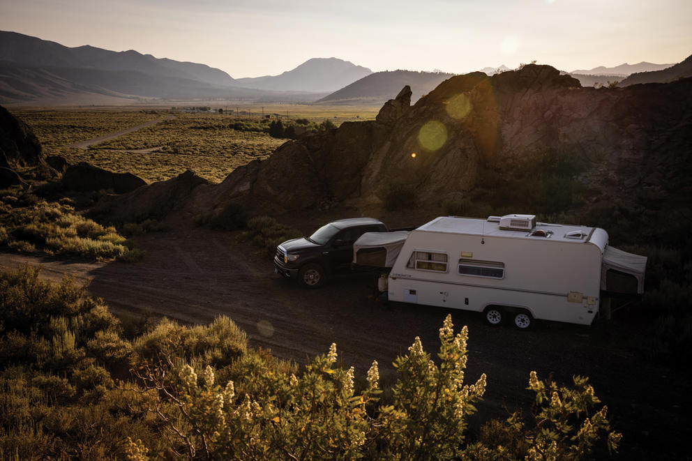 A truck and camping trailer parked by a rocky outcrop