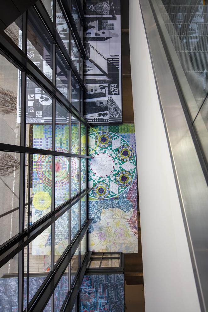 architectural photo featuring a glass wall, three boxes with colorful panels and the siding of an escalator