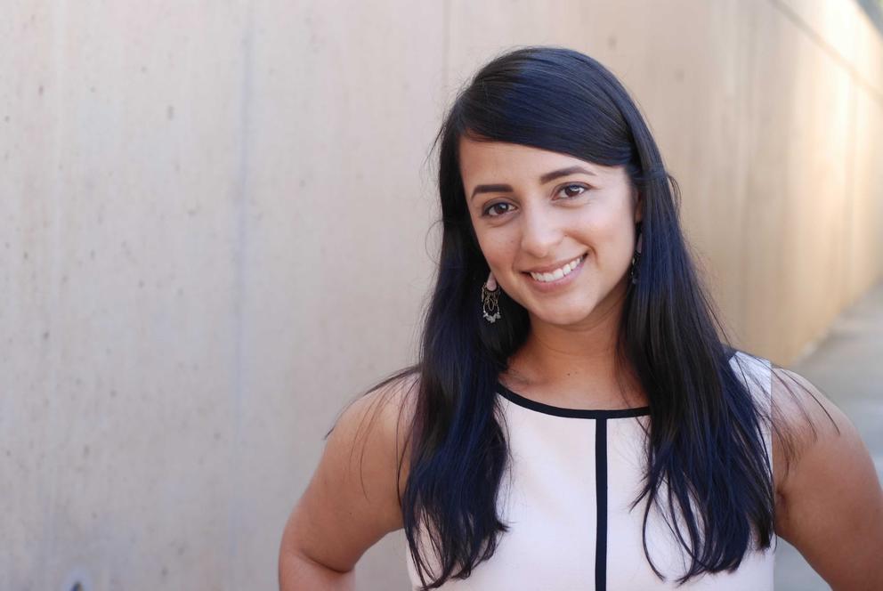 a young woman with long straight brown hair looks at the camera