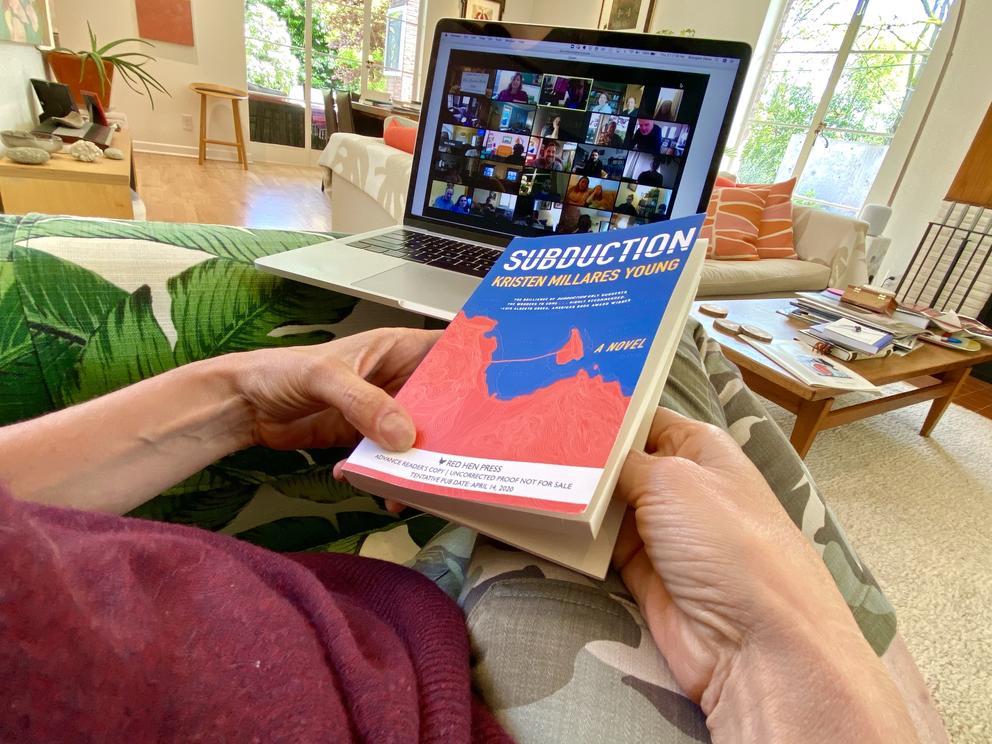 Person holding book called Subduction in front of Zoom screen