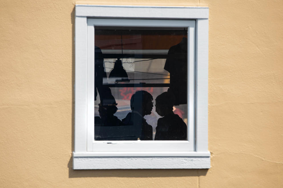 silhouettes are seen through a window with white trip