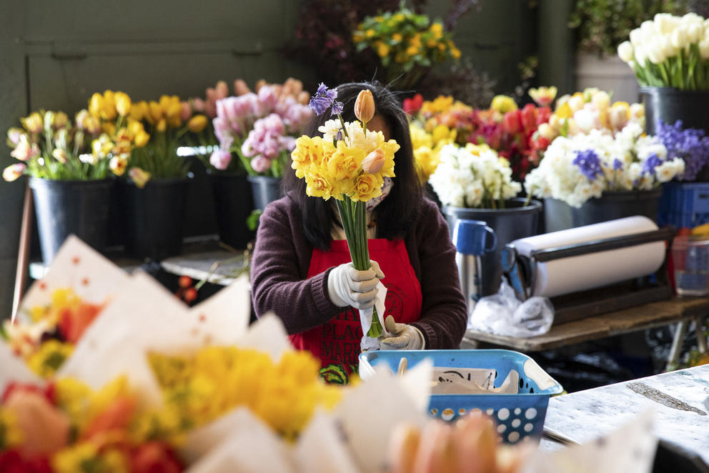 A woman surrounded by flowers with a bouquet hiding her face