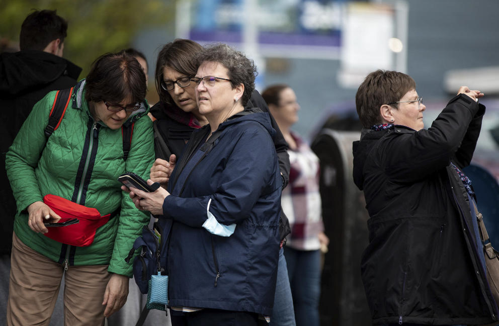 a group of women look at a phone with confused faces