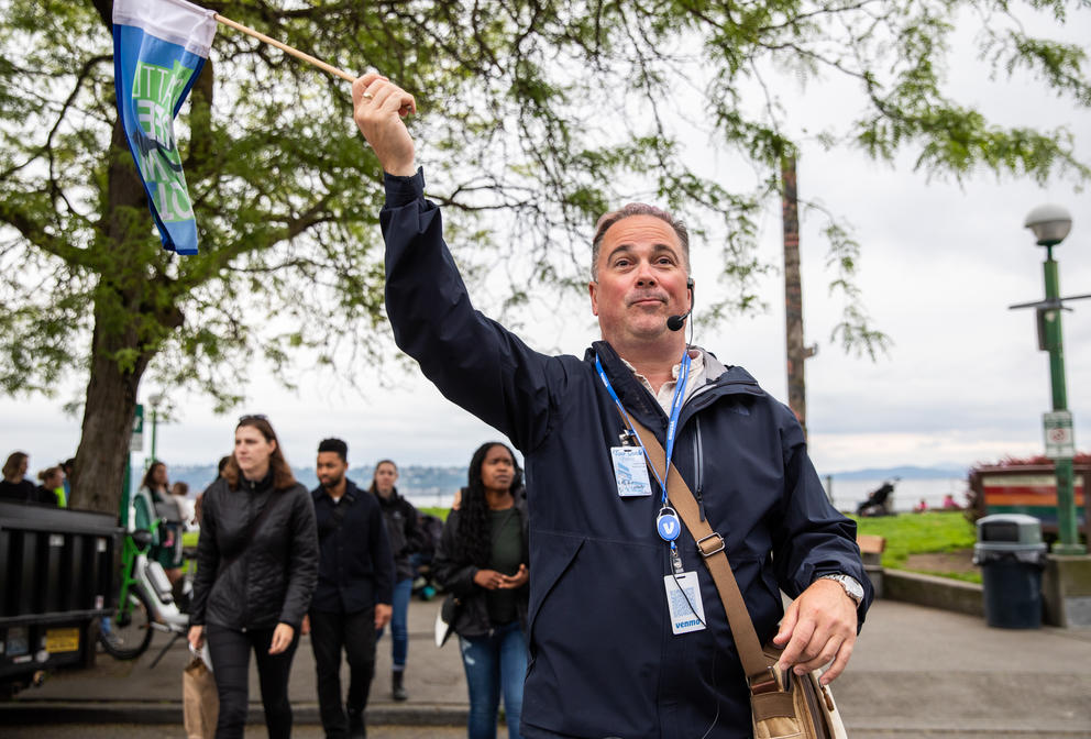 A man walks in front of a group of people holding a flag in the air