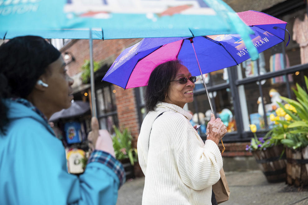 Two women hold colorful umbrellas