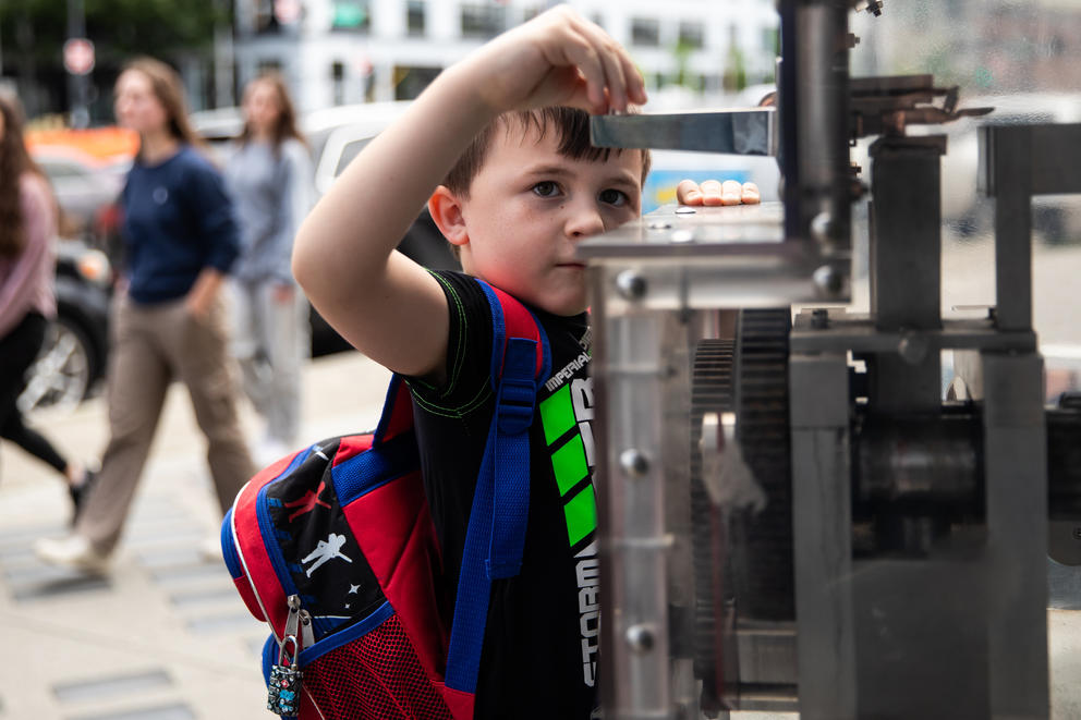 A close up of a boy putting a coin into a souvenir machine