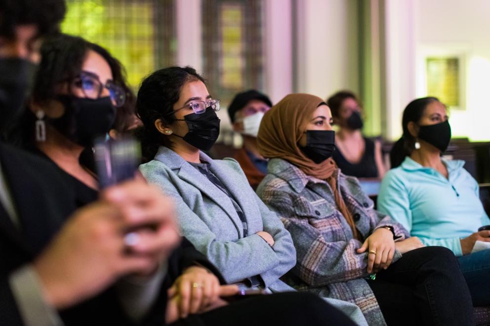 photo of masked audience members watching something unseen on stage