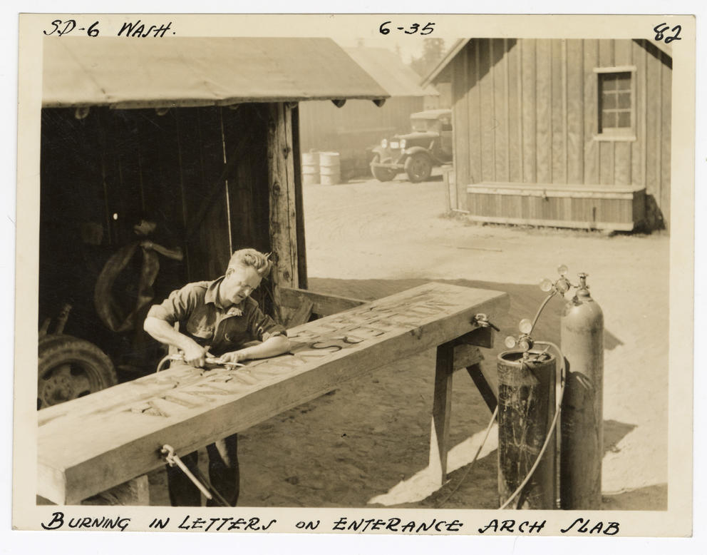 Man burning letters into a large slab of wood