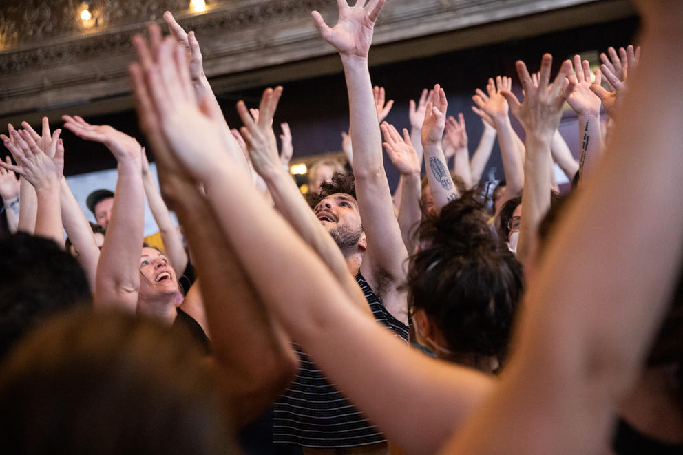 close up shot of many people in a tight circle in an exercise class, all hands raised up