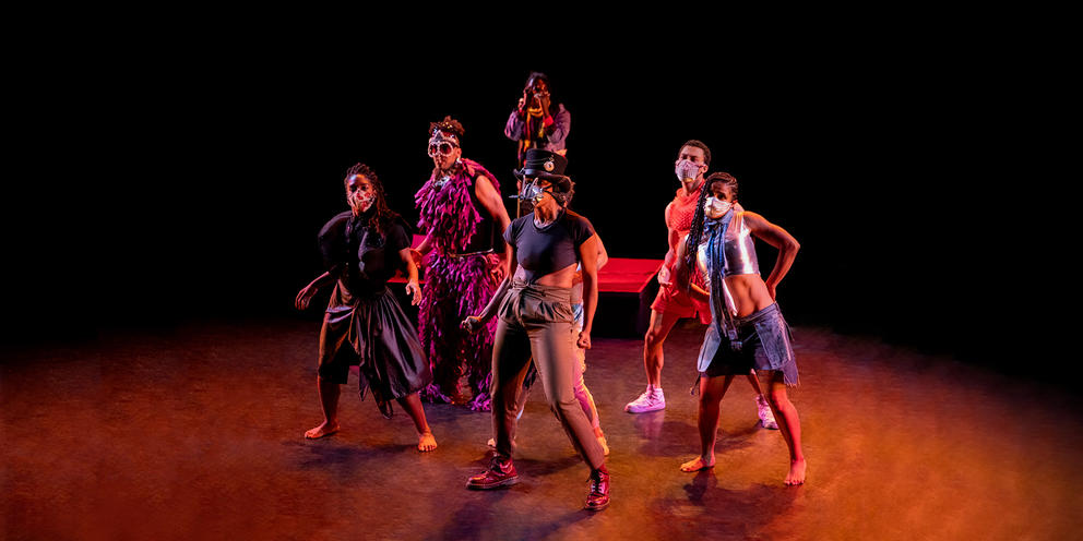 a darkened theater stage with six dancers in apocalyptic costumes