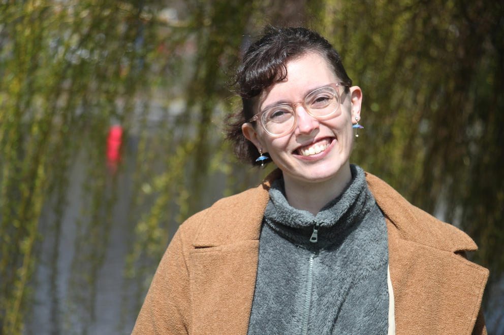 photo of a woman in a brown coat and glasses looking straight at the camera and smiling