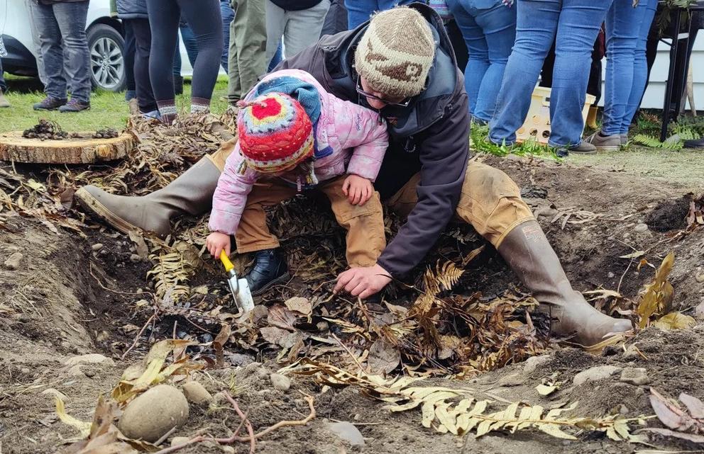 Sam Barr works with his young daughter, Seli to dig a cooking pit