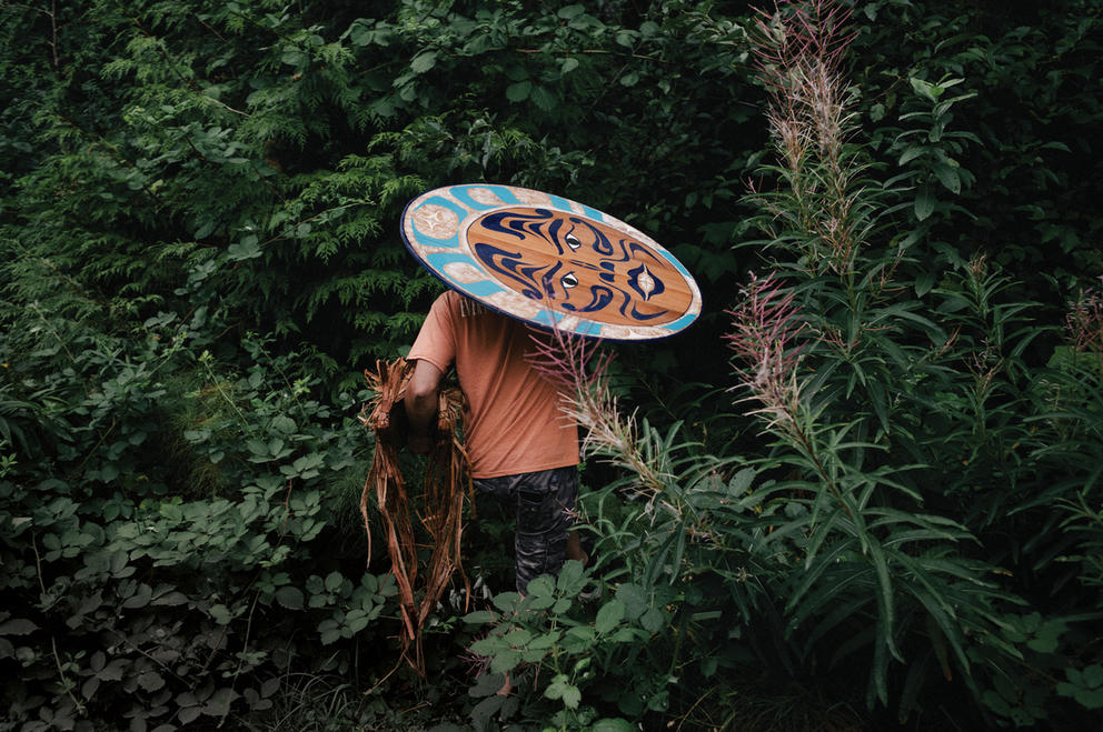 A person with a colorful shield walking into the forest