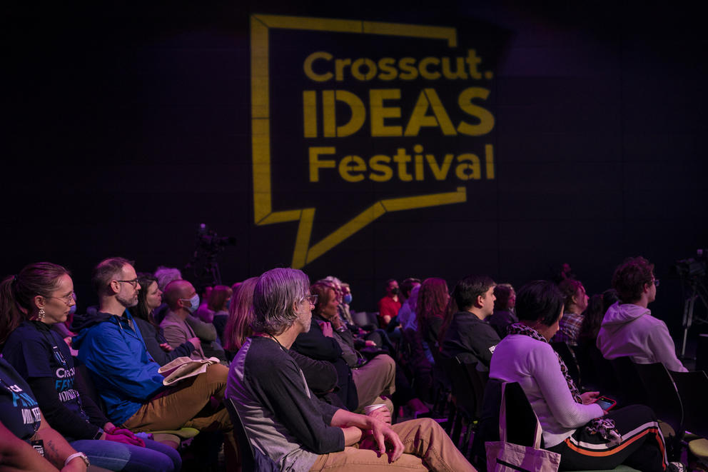 Audience members listening, sitting under a sign reading, “Crosscut Ideas Festival”