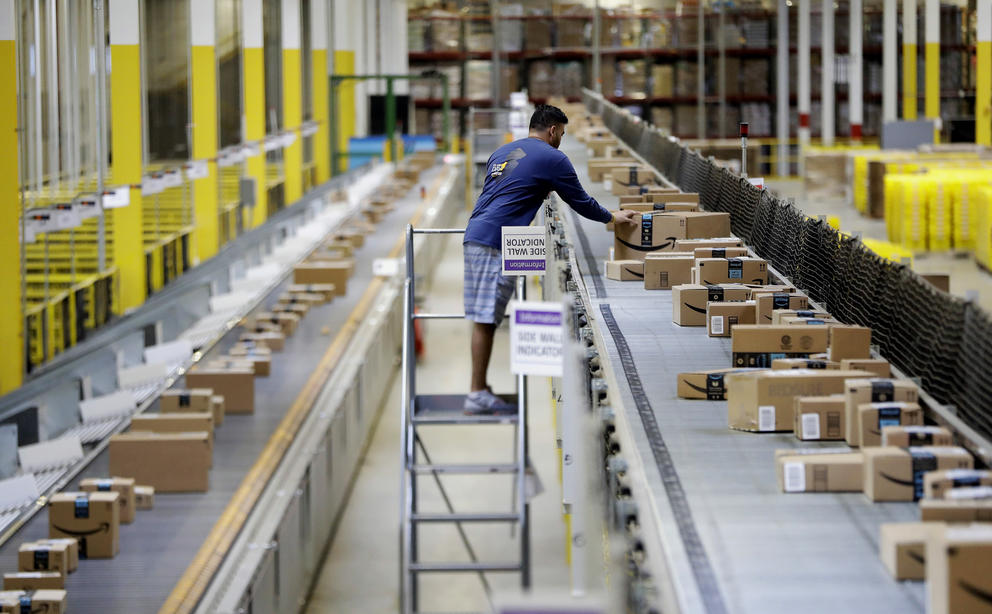 An Amazon worker fixes boxes on a conveyor belt