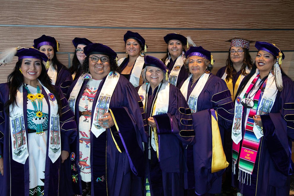 Eleven doctoral graduates line up and pose for a photo.