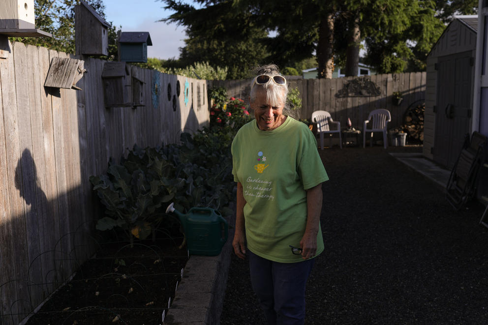 A woman stands in partial sunlight in a garden