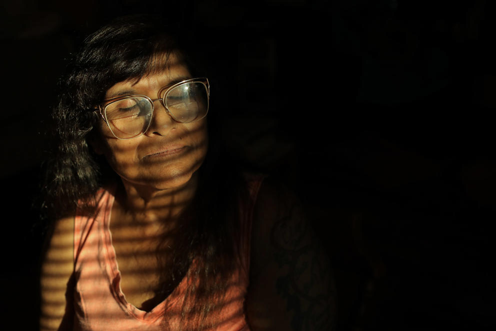 warm slatted sunlight through a window shines on a woman's face