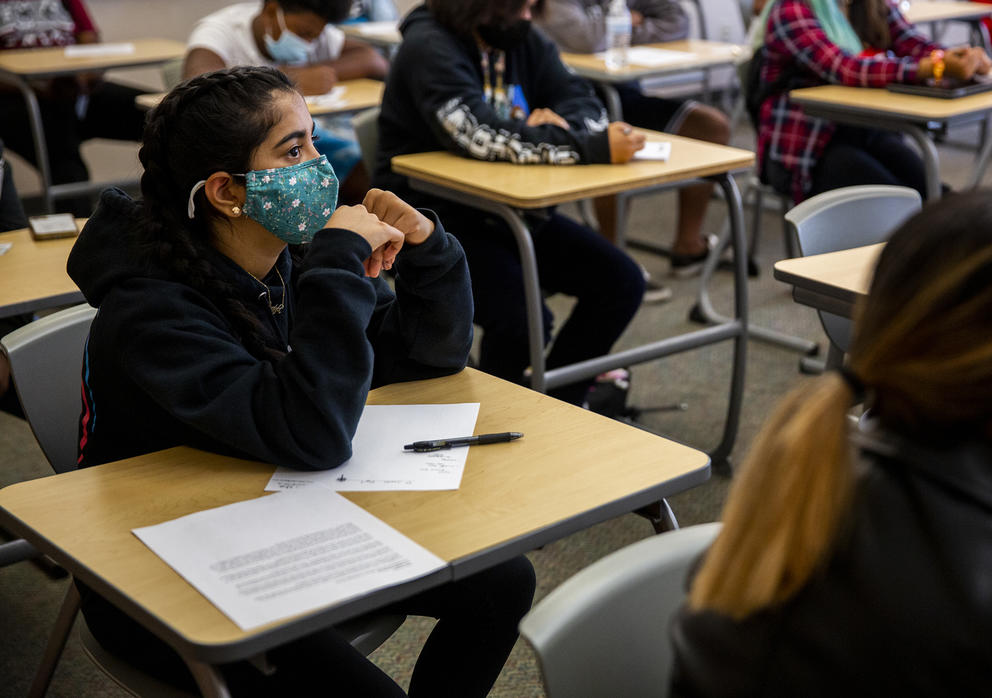 A student wearing a mask pays attention in a classroom