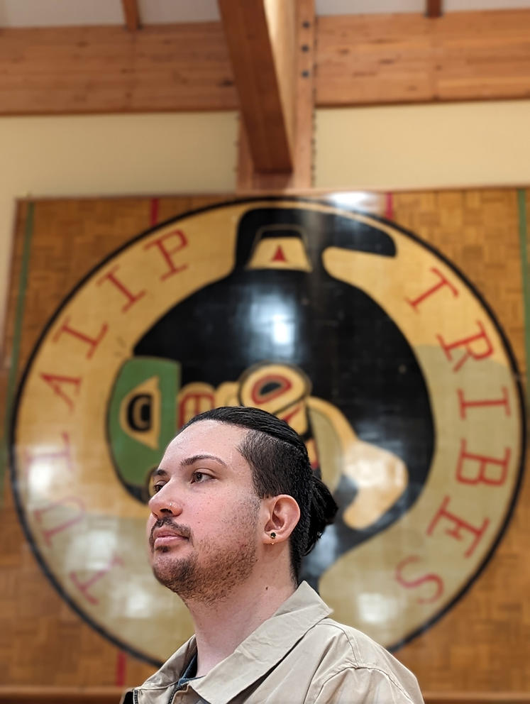A person poses for a photo in front of a sign that says Tulalip Tribes.