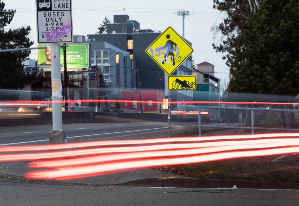 A photo of red light streaks from a passing car in front of the intersection of North 45th and Aurora Avenue North.