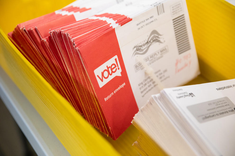 A picture of a stack of envelopes that hold ballots in a yellow box.