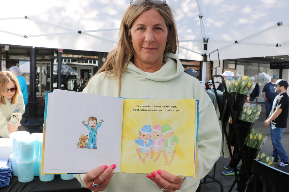 A person holds a children's book, displaying an inner page. 