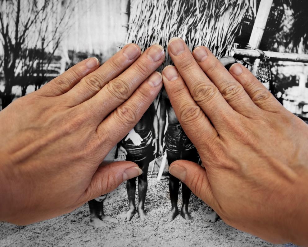 A person's hands cover a black-and-white image