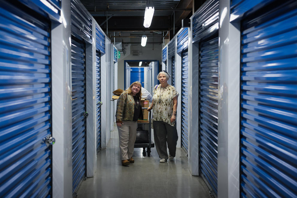 Sandra Mears and Maryann Griffin stand in a hallway lined with storage units