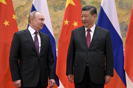 Two men in suits in front of flags