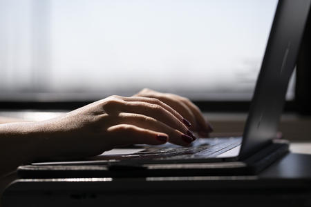 Hands typing on a laptop