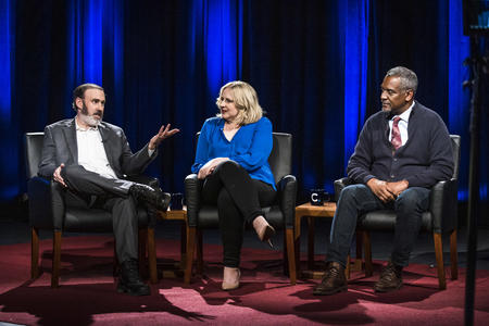 Three people seated on stage