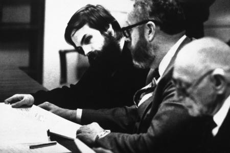 Three men at at table looking at papers