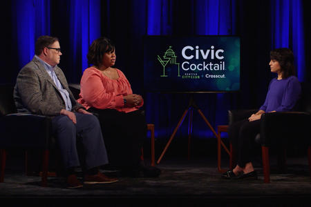 Three people sitting on stage and speaking with one another.