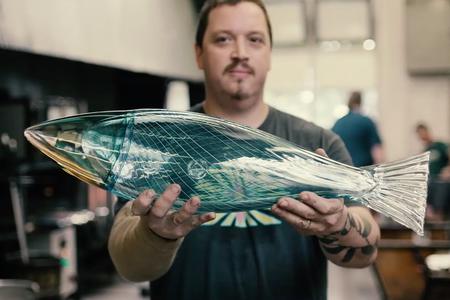 a man holds up a glass fish