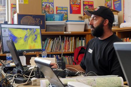 A man looks at a computer screen with mapping software pulled up