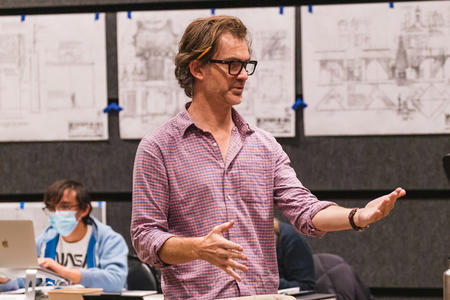 photo of a man in glasses directing a play rehearsal 