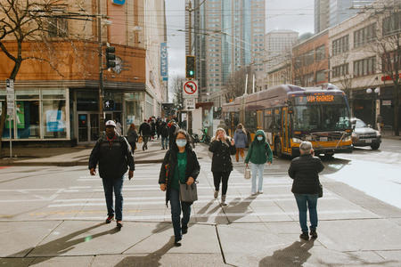 People walking in a crosswalk surrounded by high rises