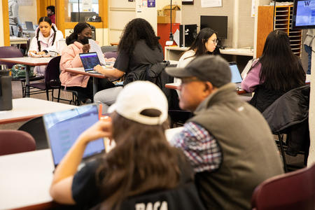 Student sitting at desks, working on laptops