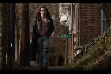 Man with guitar case walking down the sidewalk