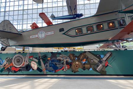 photo of a plane museum with a colorful mural below a vintage plane