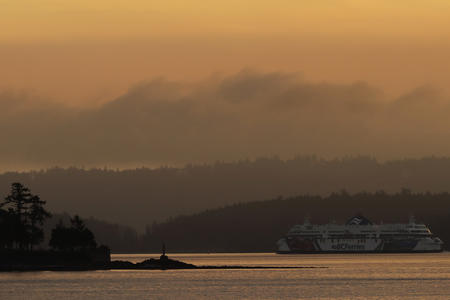 A hazy yellow sky shows shadows of mountains and a ferry boat near Vancouver Island, B.C.