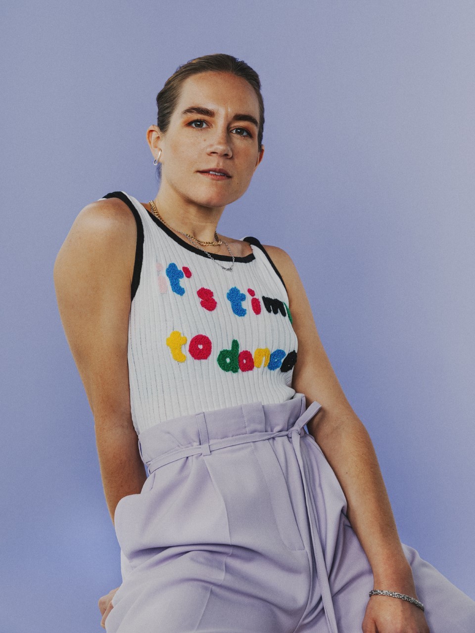 photo of a woman with her hair slicked back, she wears a tank top that reads "it's time to dance"