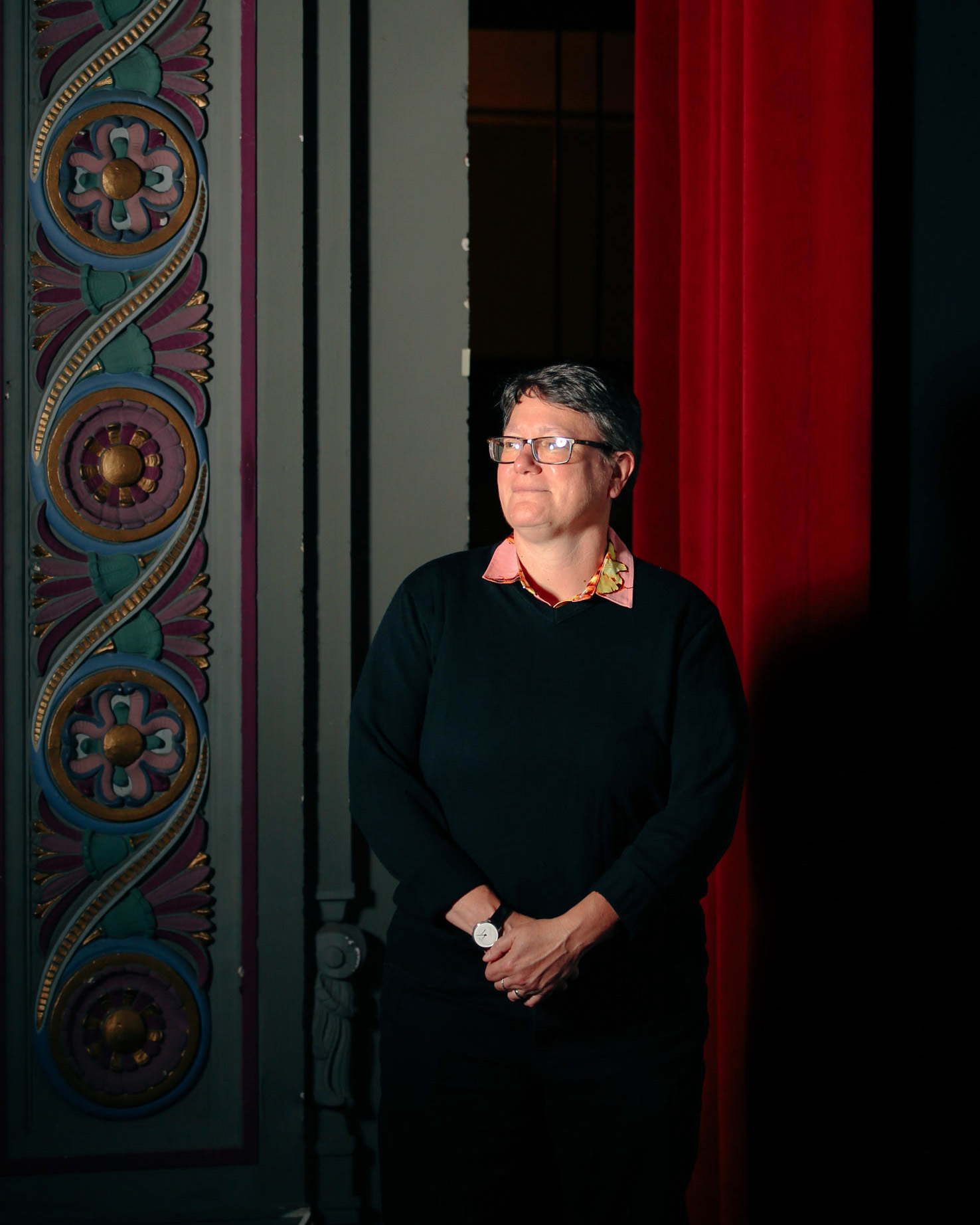 An image of a person against a theater backdrop looking away from the camera, to the side