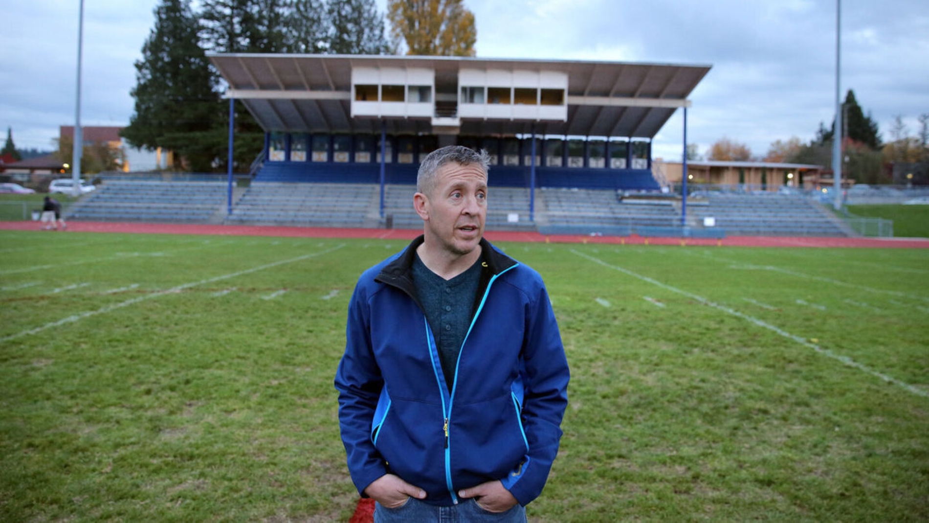 A person stands on the 50-yard line on a high school football field.