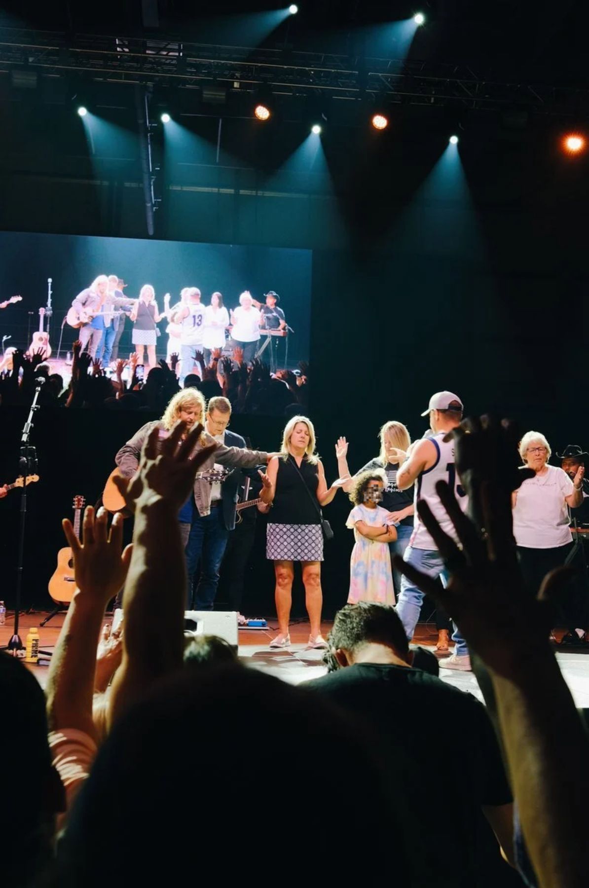 A group of people gathered on a stage and pray.