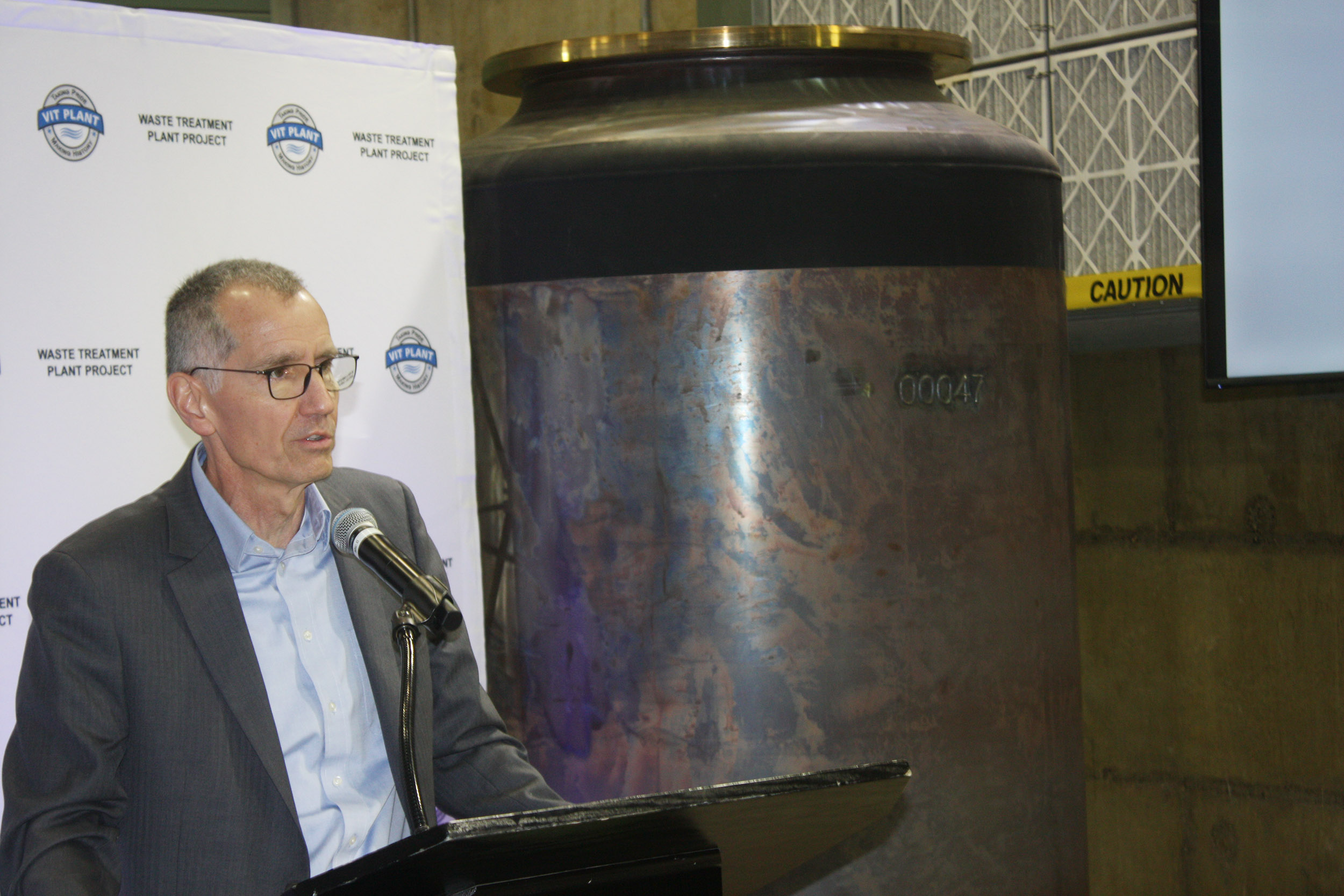 A man stands next to a large canister.